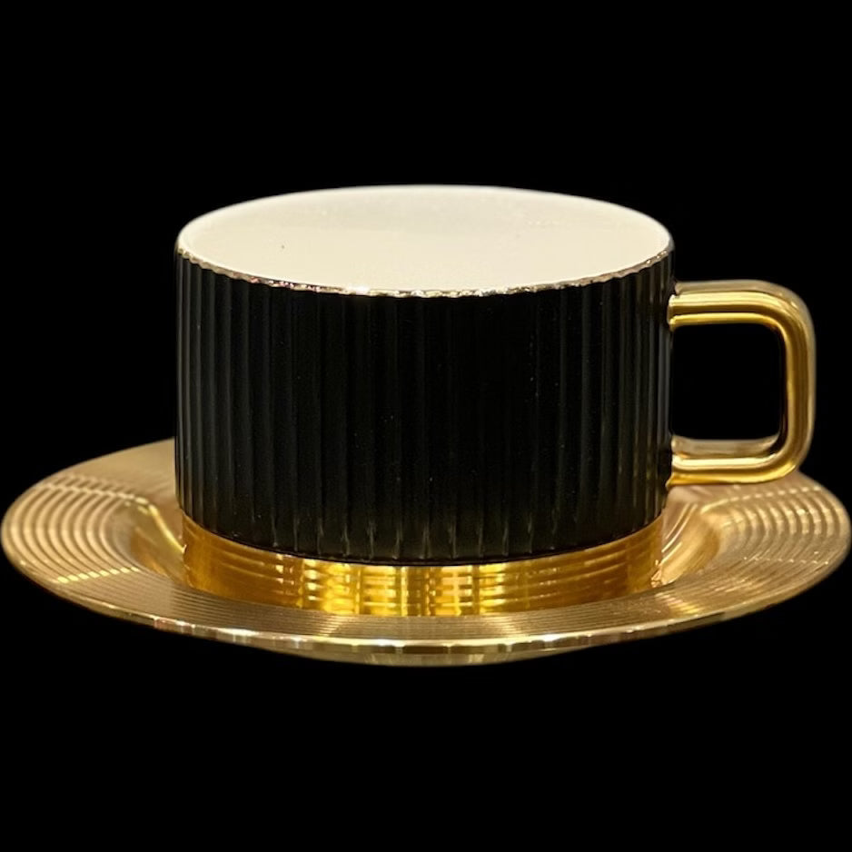 Black cup with gold handle and saucer on a black background