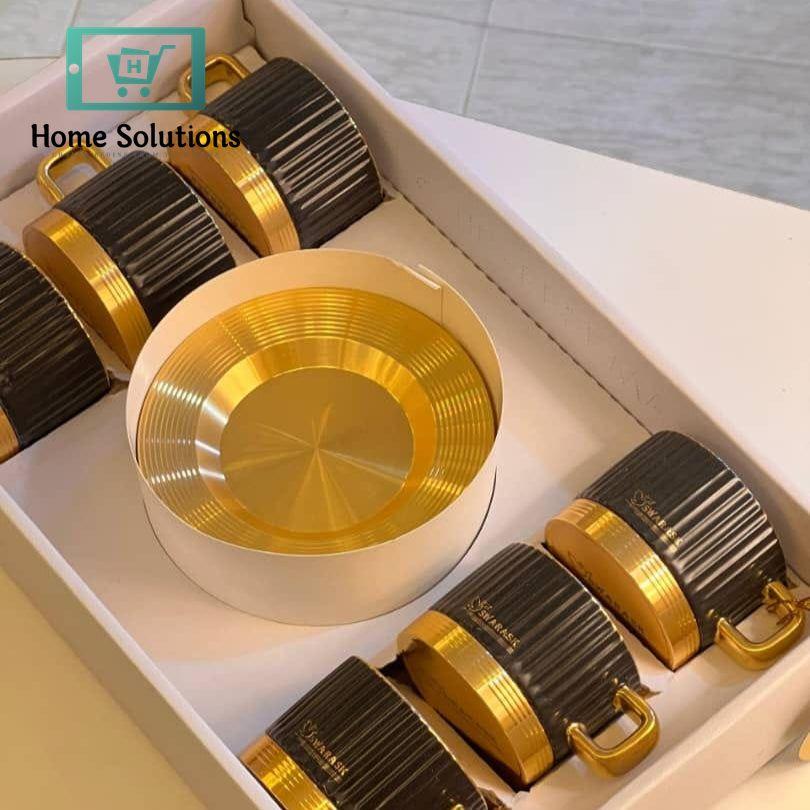 Set of gold and black cup saucers in a box