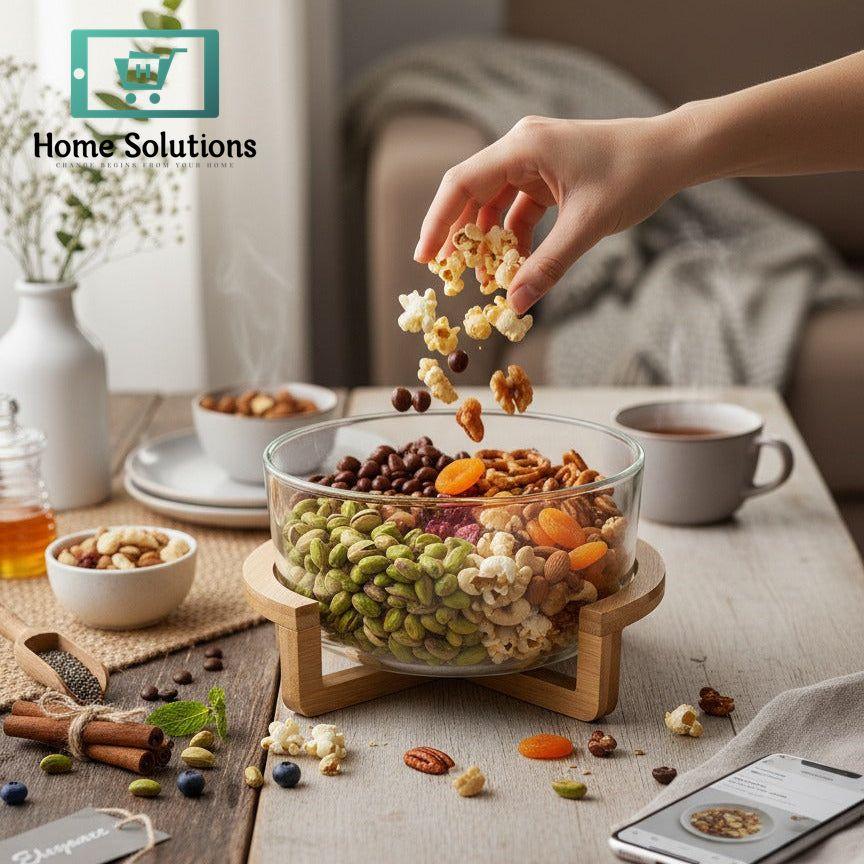 Hand picking snacks from a glass bowl on a table with a phone and cup in the background
