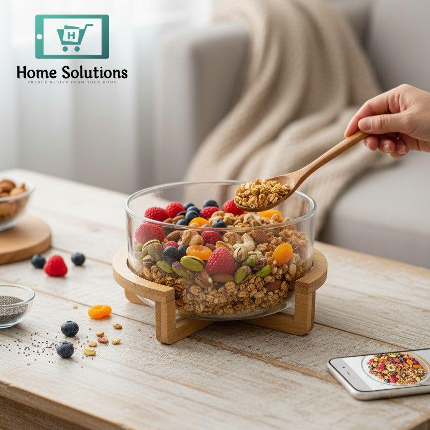 Glass bowl with mixed berries and nuts on a wooden table, with a hand holding a wooden spoon.