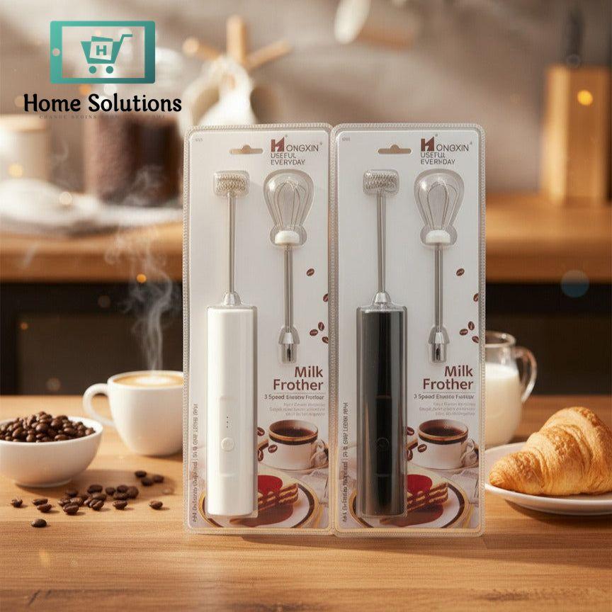 Two milk frothers in packaging on a kitchen counter with coffee and croissant in the background