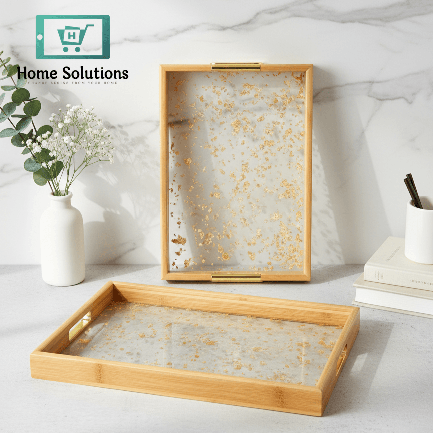 Two decorative trays with gold leaf design on a marble surface.