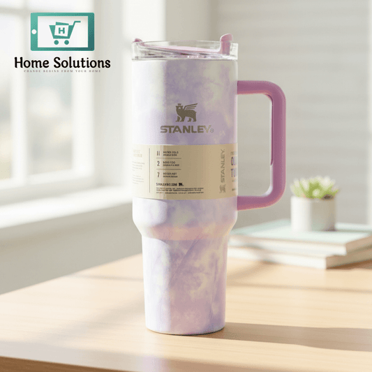 Stanley tumbler with pink and purple tie-dye design on a wooden surface with a window in the background.