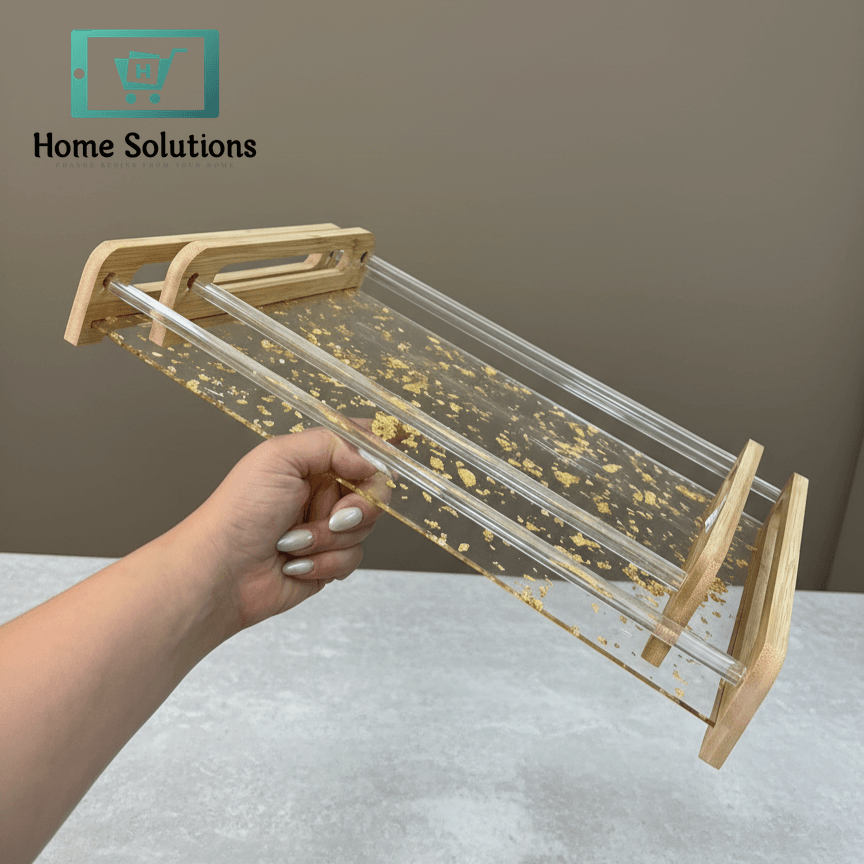 Hand holding a clear tray with gold flakes wooden sides against a neutral background