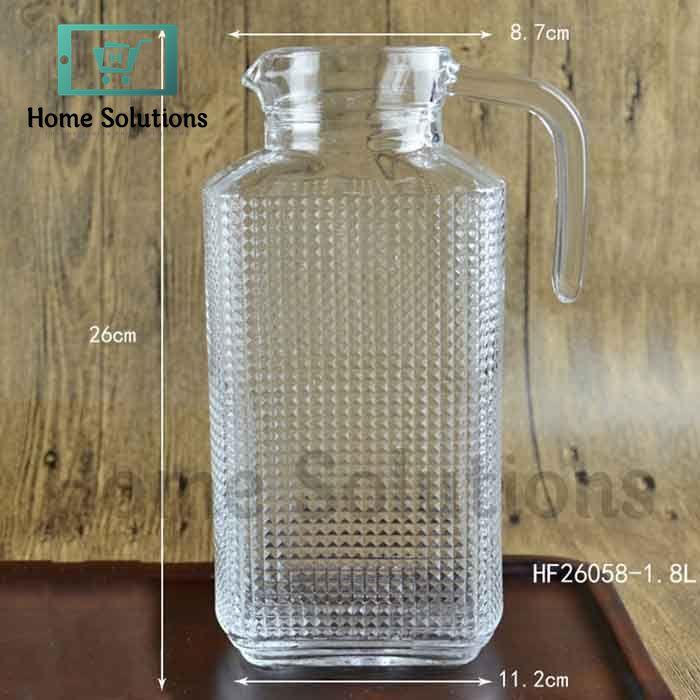 Clear glass carafe with textured surface and handle, shown with measurements on a wooden background.