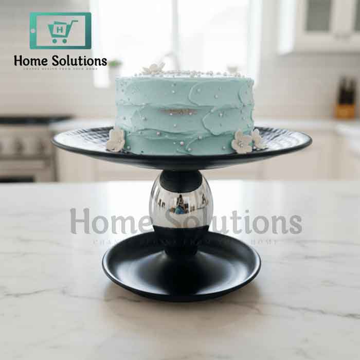 Light blue cake on a black cake stand with 'Home Solutions' branding.