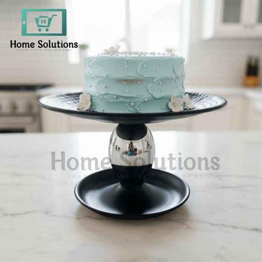 Light blue cake on a black cake stand with 'Home Solutions' branding.