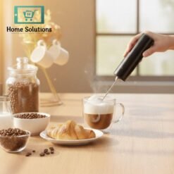 Person using a milk frother to create foam in a cup of coffee on a wooden table with coffee beans and a croissant.