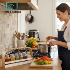 White wooden spice jar caddy with a light brown handle holding six clear glass jars with silver metal lids, organized for a modern Pakistani kitchen
