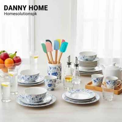 A display of popular Danny Home products, including blue and white floral dinnerware, clear drinkware, oil bottles, and colorful kitchen spatulas, set on a light wooden table in a bright home interior.