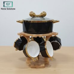 "Black and gold ceramic soup set with large soup pot, six serving bowls, spoons, and wooden rotating stand displayed on a shelf