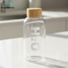 “Clear borosilicate H2O glass water bottle with a wooden cap